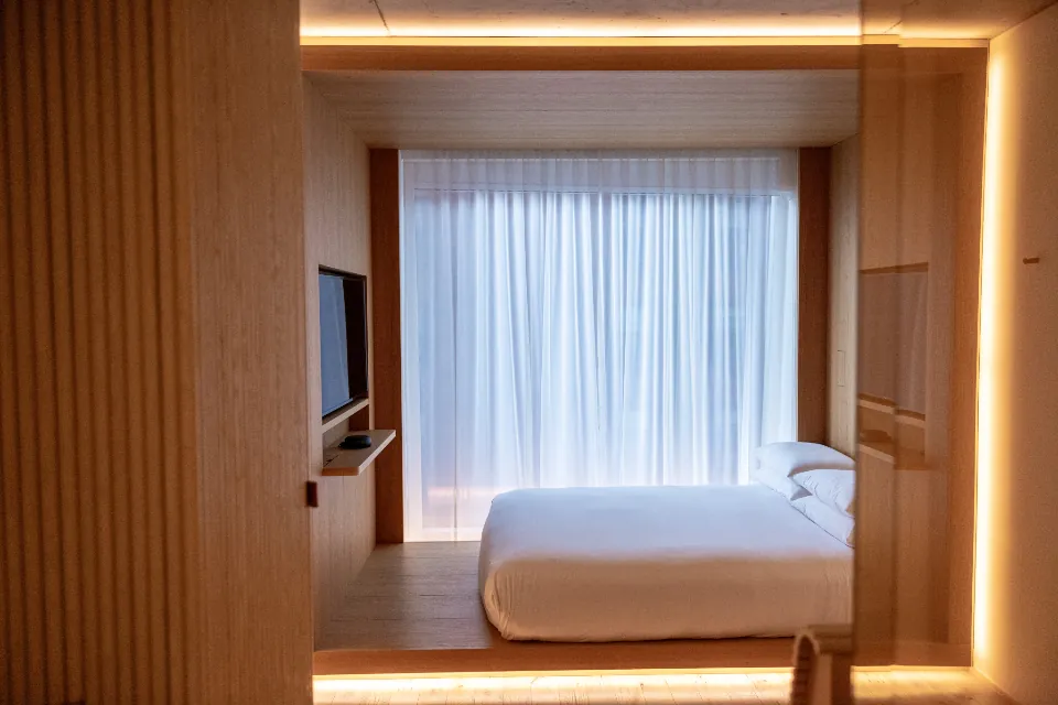 Nagomi bed — a low warm-oak bed frame in a calm, timber-lined bedroom